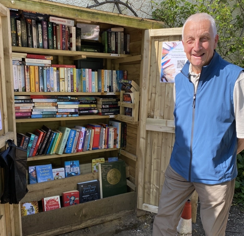 Man stands in front of community bookstall