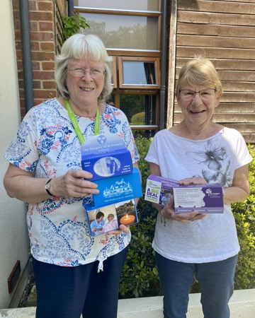 Two female volunteers hold homeboxes for the collection of donations