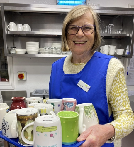 Woman carries mugs in the hospice kitchen