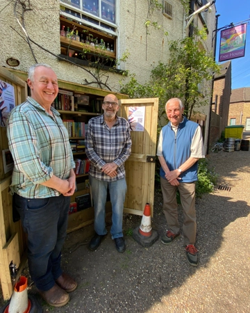 Three fundraisers stand in front of an outdoor bookstall
